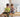 Two young children playing together on a wooden Montessori rocker in a cosy, light-filled kids’ room with natural furniture and a soft, calm atmosphere.